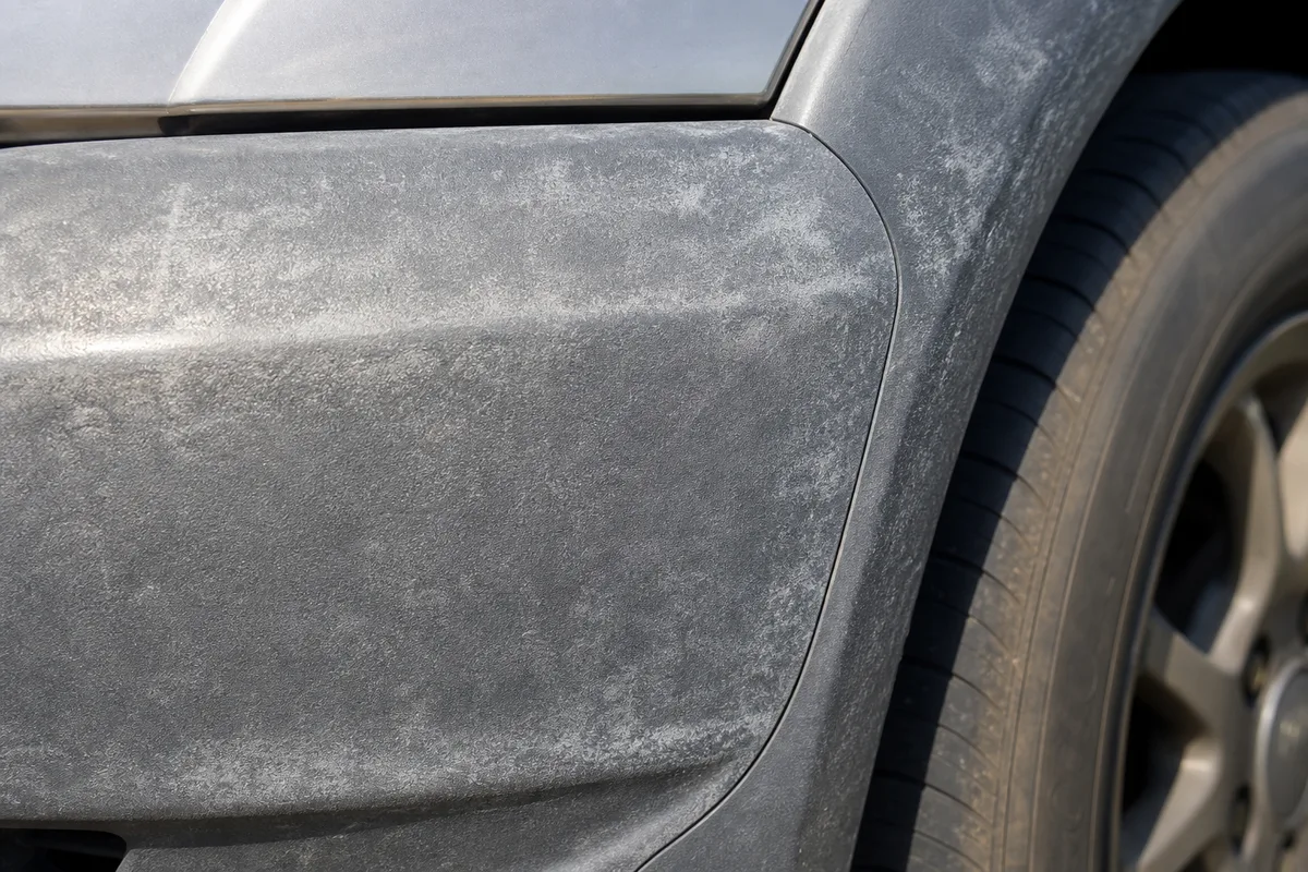 Pare-choc de voiture noir devenu gris et crayeux par le soleil, plastique extérieur terni
